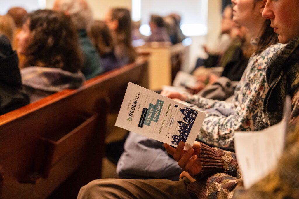 Person sitting in church pew and holding Climate Town Hall program